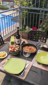 una mesa con platos de comida y una botella de vino en P.Gardens 103, en Peyia