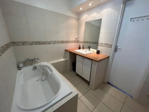 łazienka z wanną, umywalką i lustrem w obiekcie Okda YourHostHelper w Caen