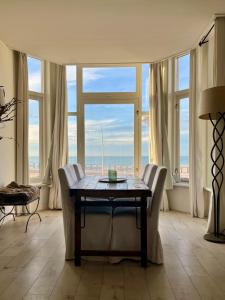 a dining room with a table and chairs and windows at Sea view Scheveningen in Scheveningen