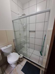 a bathroom with a toilet and a glass shower at Charmosa suíte de Tucuns. in Búzios