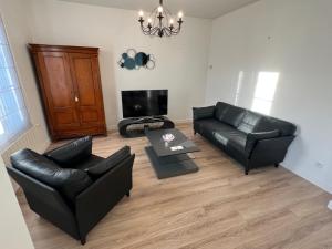 een woonkamer met zwarte lederen meubels en een flatscreen-tv bij Maison de pêcheur à 2 min de la Baie in Le Crotoy