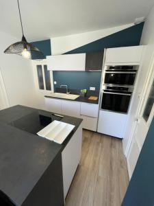 a kitchen with white cabinets and a black counter top at Maison de pêcheur à 2 min de la Baie in Le Crotoy