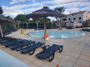 einen Pool mit Stühlen, einem Sonnenschirm und einem Spielplatz in der Unterkunft MOBIL HOME LE STEPHANOIS VALRAS in Valras-Plage