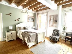 ein Schlafzimmer mit einem weißen Bett und einem Stuhl in der Unterkunft La Demeure du Capitaine in Neuville