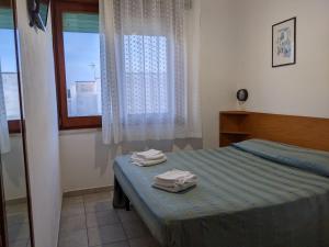 una camera da letto con un letto e due asciugamani di Albergo casa del turista a Torre dell'Orso