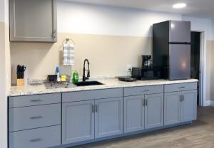 a kitchen with white cabinets and a stainless steel refrigerator at Lazy Cuckoo Inn - Sleek and Stylish Studio Apartments in Fort Myers Beach