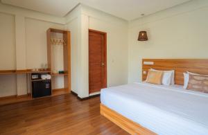a bedroom with a large white bed and wooden floors at Niru Isle Maldives in Gaafaru
