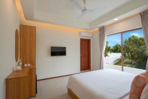 a bedroom with a bed and a large window at Niru Isle Maldives in Gaafaru