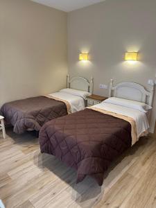 two beds in a room with wooden floors at Hostal Toledo Plaza in Toledo