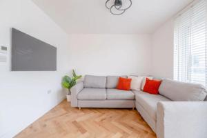 een witte woonkamer met een bank met oranje kussens bij Central 3BD Flat with Balcony in Paddington in Londen