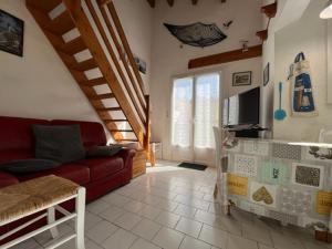 salon z czerwoną kanapą i telewizorem w obiekcie Charmante maison 3 pièces, 2 pas plage et forêt, 4 couchages, WIFI, stationnement, ménage inclus - St Georges d'Oléron - FR-1-246A-152 w mieście Saint-Georges-dʼOléron