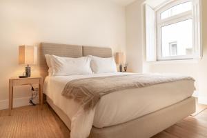 a bedroom with a large white bed with a window at Villa Sofia Cascais in Cascais