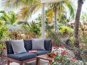 a blue couch sitting on a patio with palm trees at Cocoa Cove Resort in Saint Georgeʼs