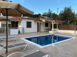 a pool with chairs and an umbrella and a house at Villa Valmas Private Escape in Skiathos