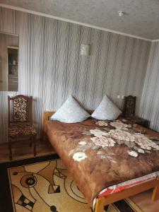 a bedroom with a large bed and a chair at Cottage 5 in Karpaty