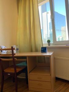 uma secretária com uma janela e uma secretária com uma cadeira em Комфортабельная комната в квартире em Astana