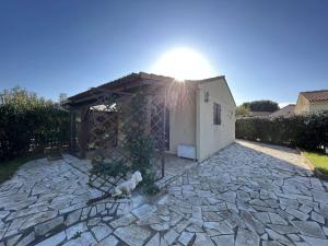 mały budynek z dachem na kamiennym patio w obiekcie Pavillon 3 Pièces avec Jardinet, Terrasse, et Piscine - 4 Personnes, Vendres - FR-1-701-26 w mieście Vendres