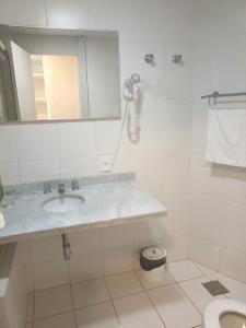 Baño blanco con lavabo y espejo en Não Disponível, en Florianópolis