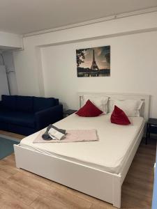 ein weißes Bett mit roten Kissen in einem Zimmer in der Unterkunft Tranzzit Airport Apartament I in Otopeni