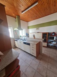 a large kitchen with white cabinets and a wooden ceiling at Seaview apartment Marta in Crveni Vrh