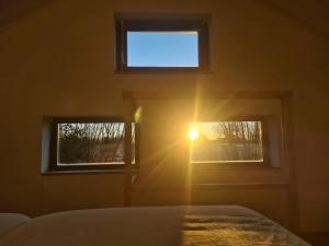 Un dormitorio con el sol brillando a través de dos ventanas en Gastenverblijf 'De Mergelheuvel', Zuid-limburg, en Valkenburg