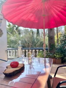 a wooden table with a red umbrella on a patio at Appartement in Flayosc