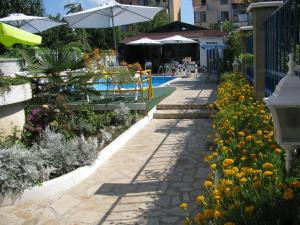 a patio with tables and umbrellas in a garden at Villa Sens in Chernomorets