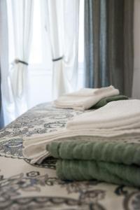 a bed with white sheets and green towels on it at bocca di lupo in Genova