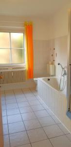 ein weißes Bad mit einer Badewanne und einem Fenster in der Unterkunft Ferienwohnungen Villa Goldbrunnen in Bad Elster