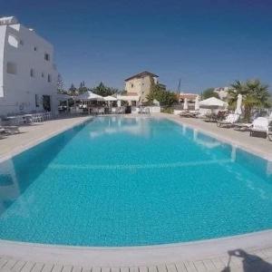 a large blue swimming pool with chairs and umbrellas at Maria Holiday Apartments in Protaras
