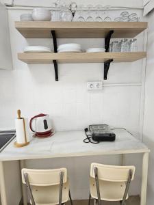 a kitchen with two chairs and a table and shelves at Apartamento Familiar en Triana in Seville