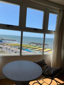 Cette chambre dispose d'une table et d'une fenêtre avec vue sur la plage. dans l'établissement Hotel Atlántico Suites, à Mar del Plata