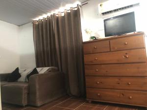 a bedroom with a dresser and a couch and a dresser at Apartamento aconchegante com deck in Rio de Janeiro