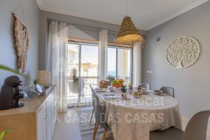 a dining room with a table and a large window at Villa du Soleil by ACasaDasCasas in Ericeira