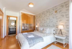 a bedroom with a large white bed and a bathroom at Villa du Soleil by ACasaDasCasas in Ericeira
