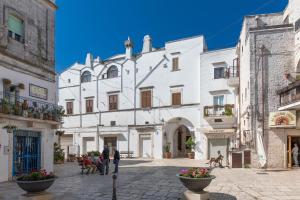 eine Stadtstraße mit weißen Gebäuden und Menschen, die Hunde gehen in der Unterkunft Bomboniera di Cisternino in Cisternino