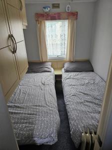two beds in a small room with a window at Esmeralda's Caravan Hire Mablethorpe in Mablethorpe