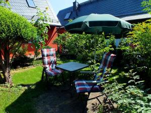 2 sillas y una mesa con sombrilla en un patio en Ferienhaus Zum Gründel, en Prossen