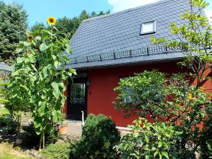 una casa roja con techo negro y girasol en Ferienhaus Zum Gründel, en Prossen