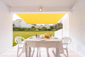 Biały stół z białymi krzesłami i żółtym sufitem w obiekcie Villa Alfamar by HelloVacations w Albufeirze