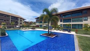 a swimming pool with a palm tree in front of a building at Reserva dos Carneiros - Ao lado da Igrejinha in Praia dos Carneiros