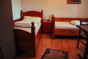 two twin beds in a room with wooden floors at ZOLI'BÁ Apartman in Gyöngyösfalu