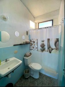 La salle de bains est pourvue de toilettes blanches et d'un lavabo. dans l'établissement Habitación Privada en Flores, à Flores
