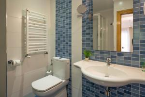 a blue tiled bathroom with a toilet and a sink at Hotel Arco Navia in Navia