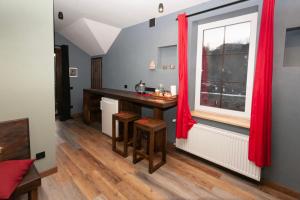 a kitchen with a table and a window with red curtains at Гостьовий дім Білий пацюк in Kamianets-Podilskyi