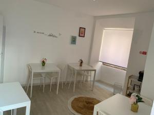 5 Senses Hostel في سيتوبال: غرفة بيضاء مع طاولتين ونافذة