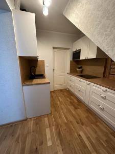 uma grande cozinha com armários brancos e pisos de madeira em Apartment Kesklinna läheduses em Tartu