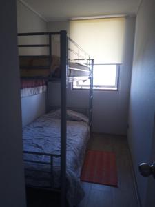 a small room with a bunk bed and a window at Depto. con vista al mar 4° piso, Tomé, Dichato in Tomé