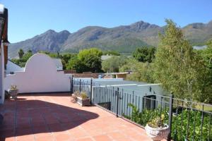 a patio with a fence and mountains in the background at Petite France:luxury thatched 4BRcottage with pool in Franschhoek