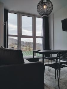 a living room with a table and chairs and a large window at Apartamenty Ustroń Jaszowiec 92 abc in Ustroń